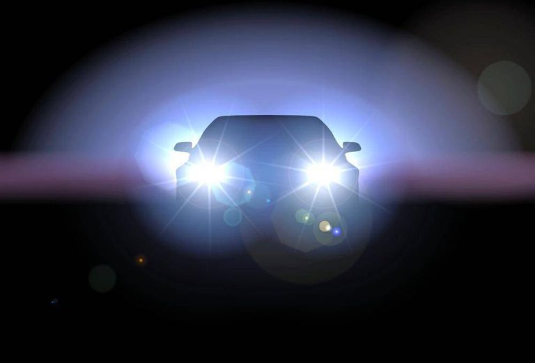 A car with bright headlights shining directly into the camera