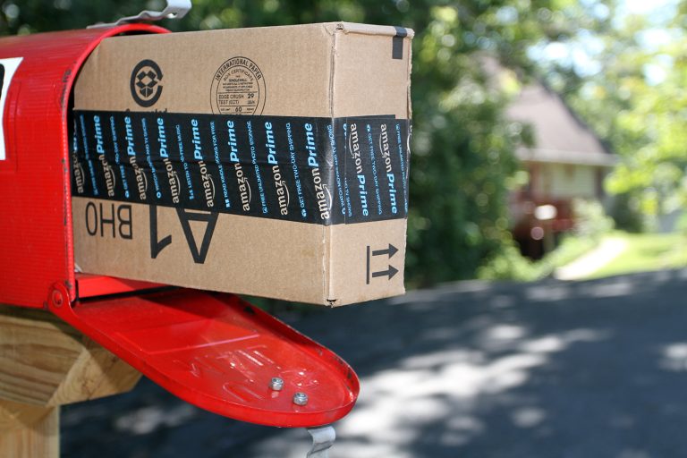 An Amazon shipping box in the mailbox in front of a home after being delivered.