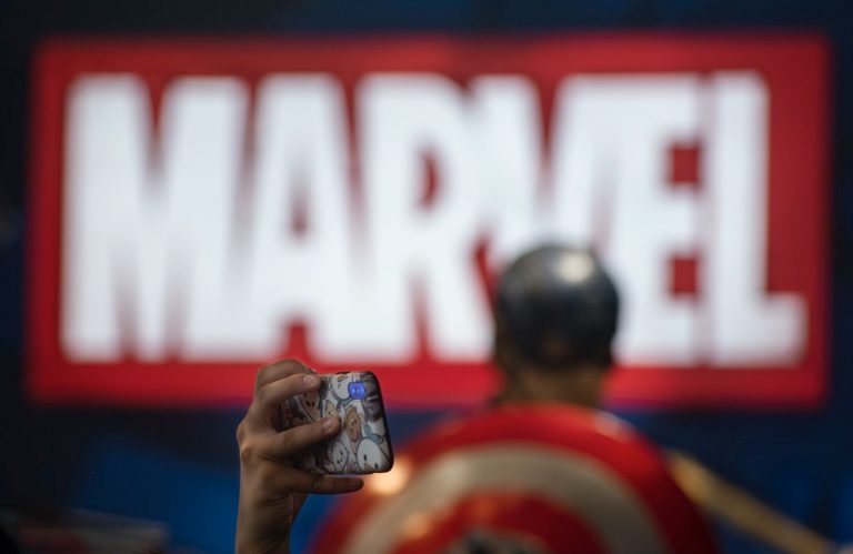 A visitor taking photos at Marvel's booth during a convention