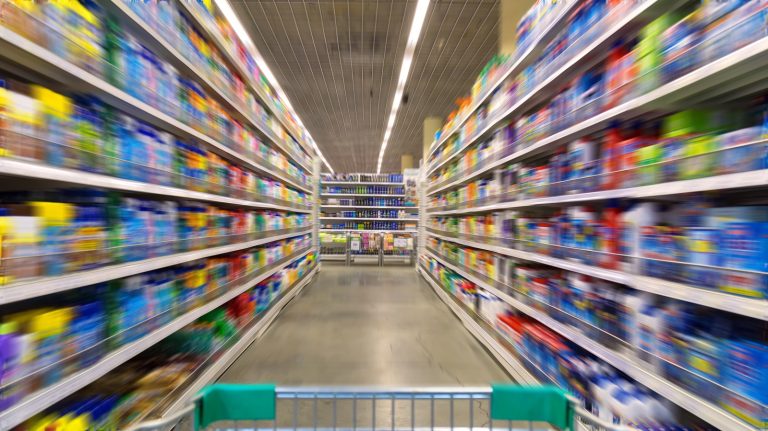 Shopping cart view fn a supermarket aisle and shelves