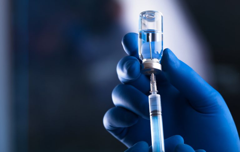 A doctor is shown holding a syringe and a drug vial.