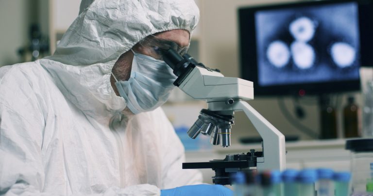 Dokter in een gezichtsmasker met een microscoop