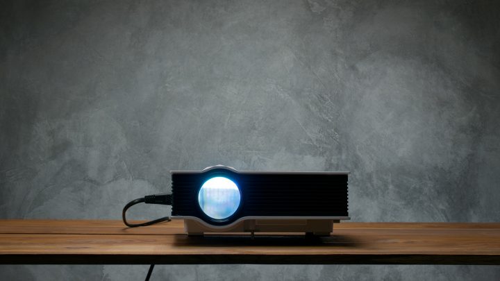 A home theater projector positioned on a shelf in a modern home