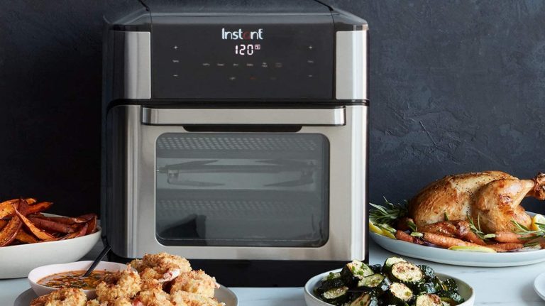 Instant Vortex Plus Air Fryer Oven on a table next to air-fried foods