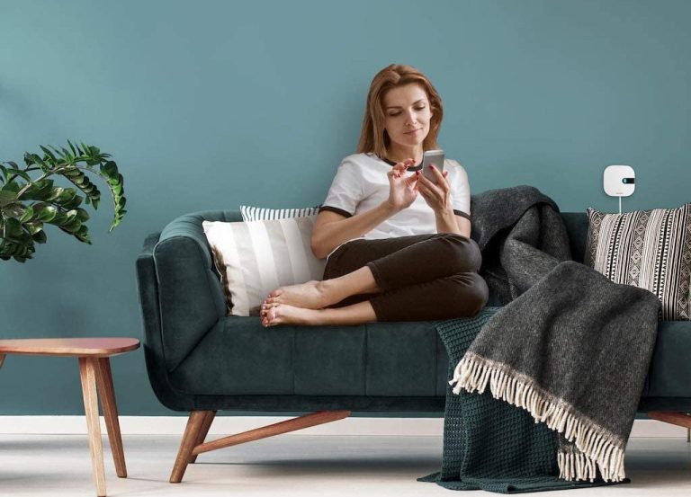 A woman controlling the Sensibo Air from a smartphone while sitting on her couch