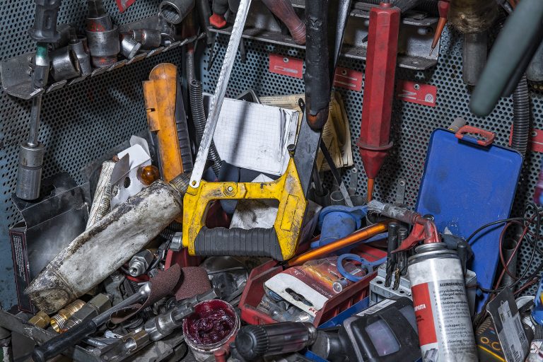 Tools including a saw and wrenches in a cluttered toolbox