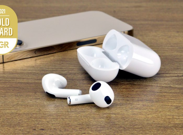 Apple AirPods 3 on a table next to an iPhone 13 Pro