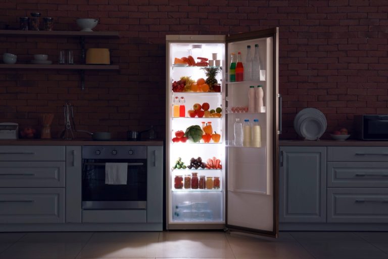 A fridge containing drinks open at night