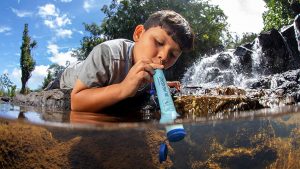 A child using the LifeStraw in a stream