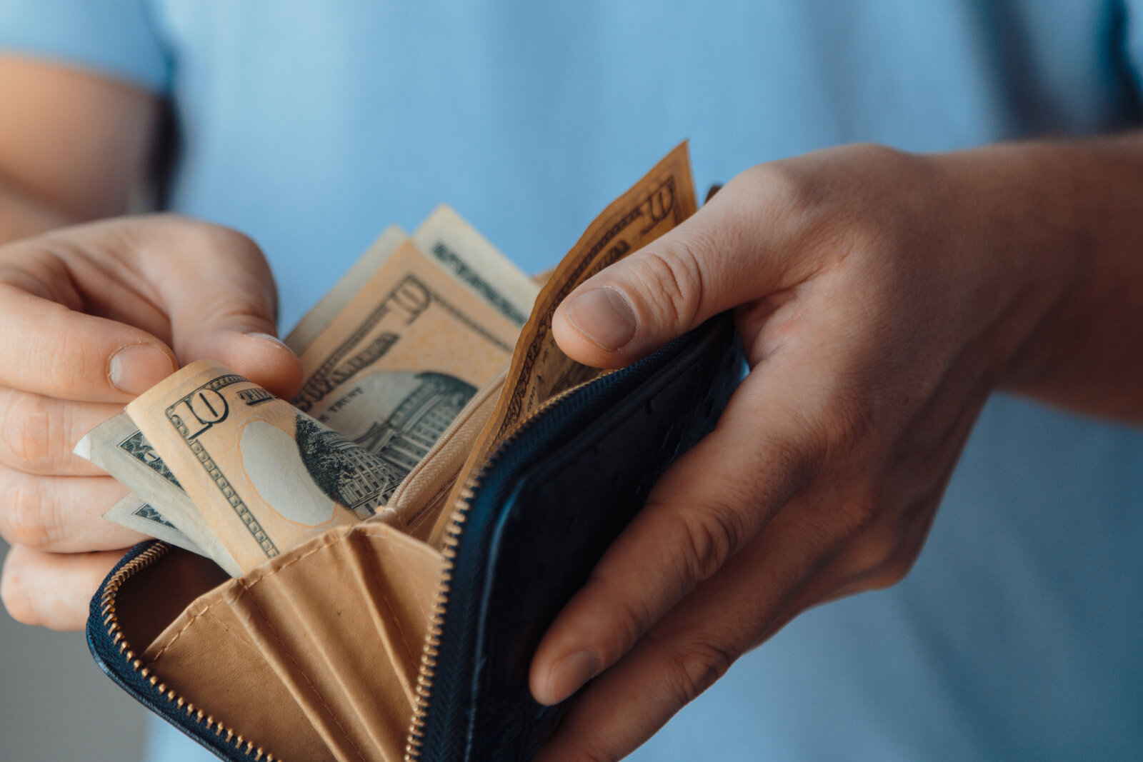 A man is shown opening a wallet full of cash.