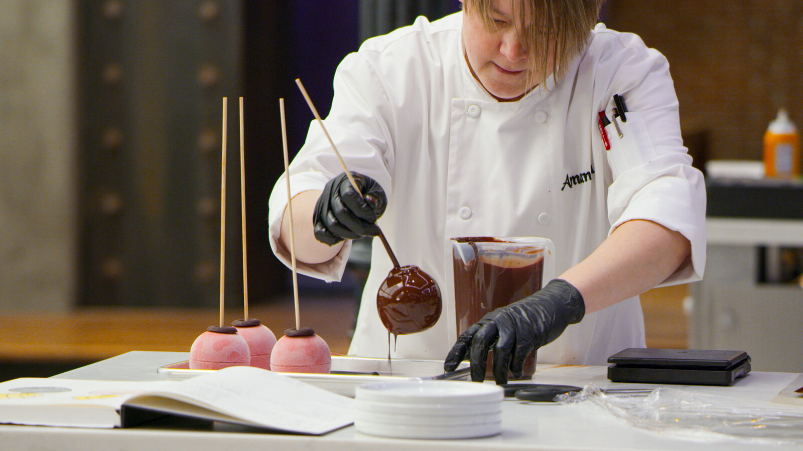 baker in white coat picking up chocolate