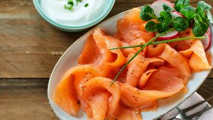 Smoked salmon on a plate next to some cream cheese