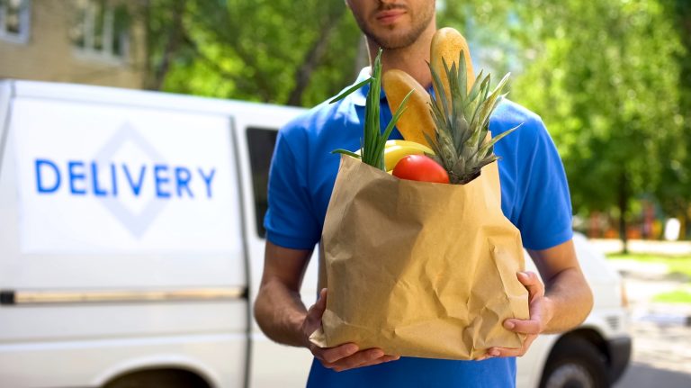 A delivery person carrying a grocery bag