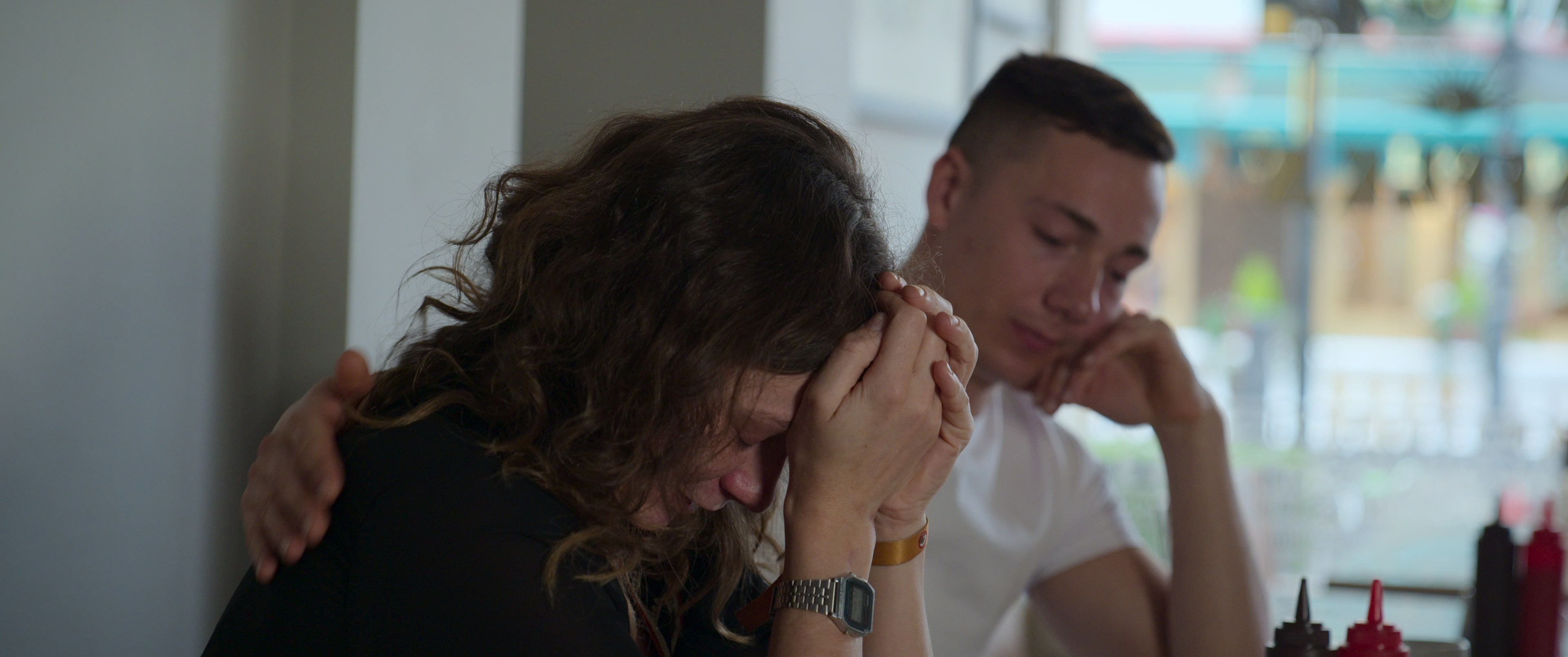 a man consoles a woman with her head in her hands