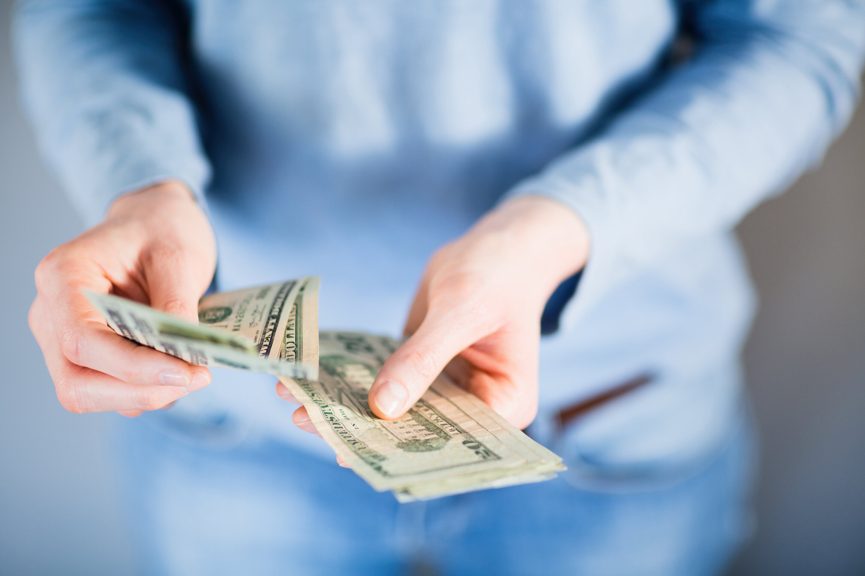 A person is shown counting out money in their hands