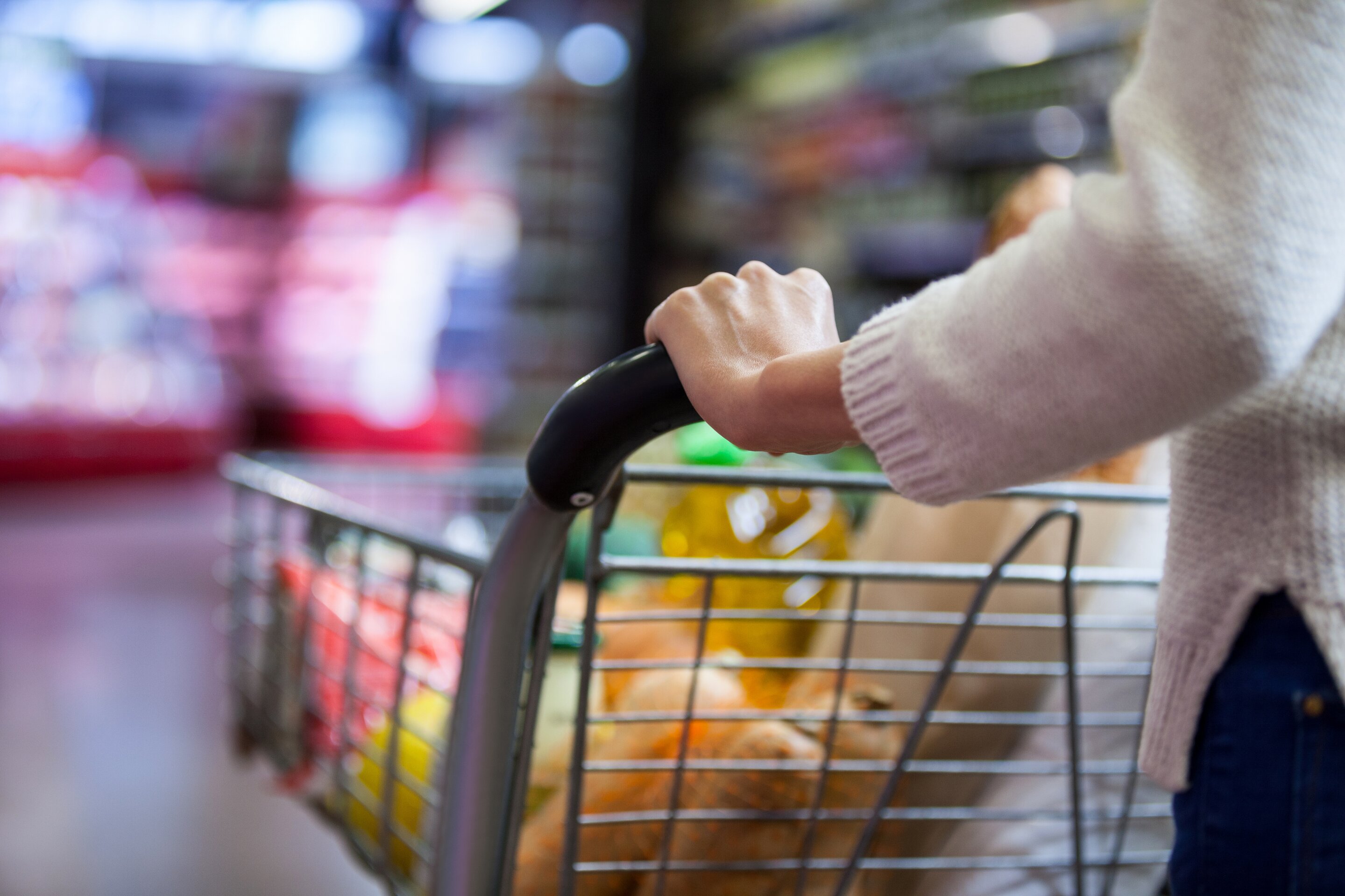 A woman is shown pushing a cart full of groceries