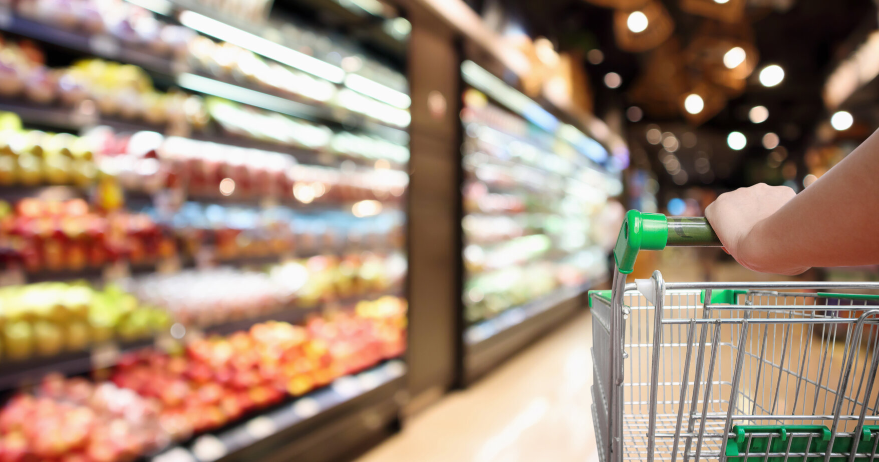 a shopper pushes a cart down a grocery aisle