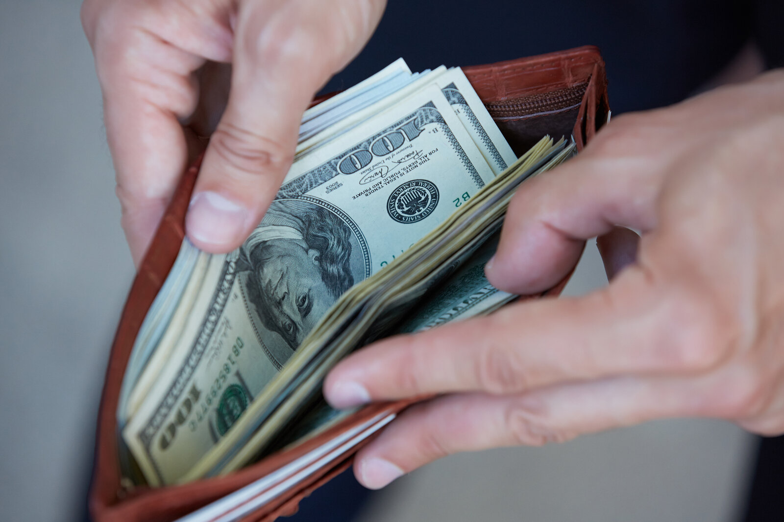 A close-up of a man opening a wallet with cash