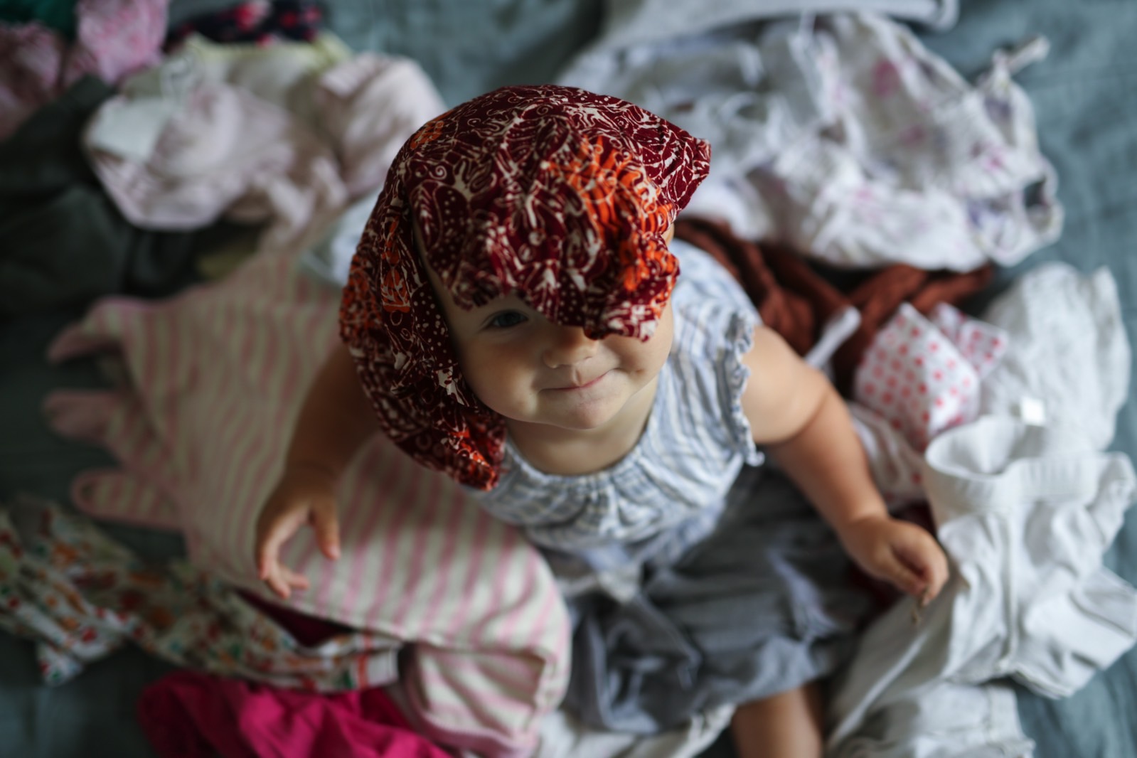 A baby in the middle of a big pile of clothes