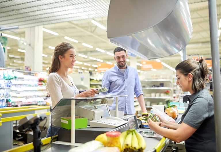 Grocery store supermarket shoppers check out at the register