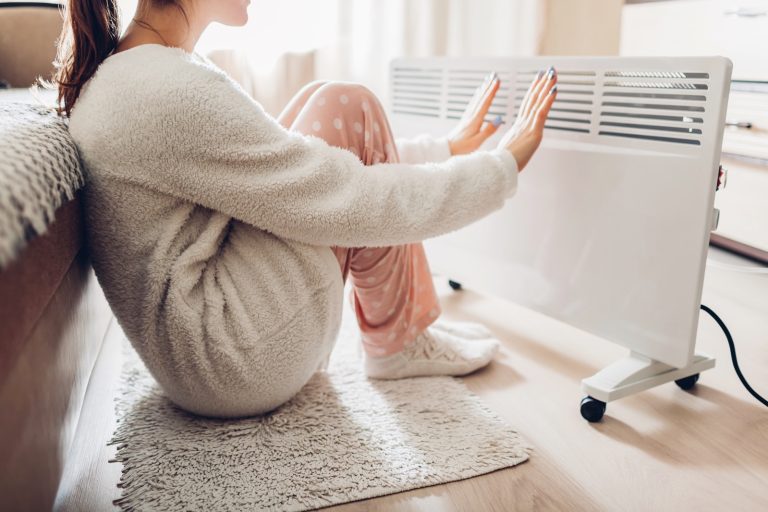 A woman using an electric heater at home