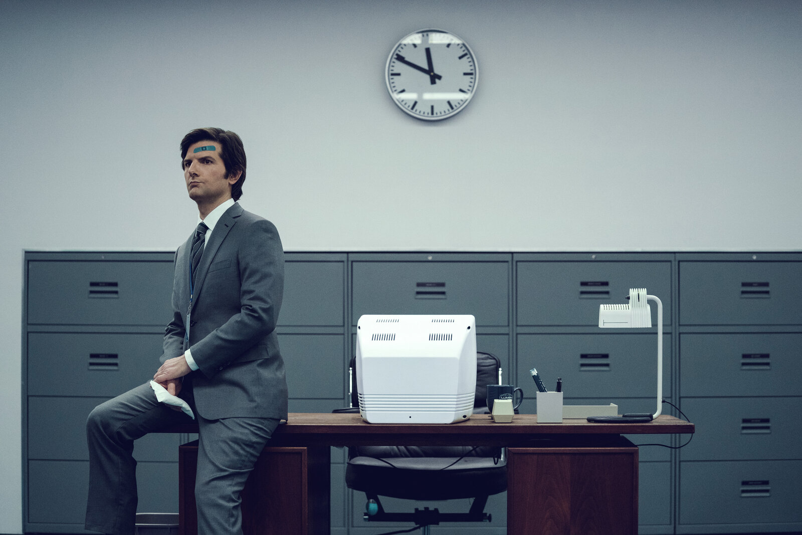 a man in a suit sits on a desk