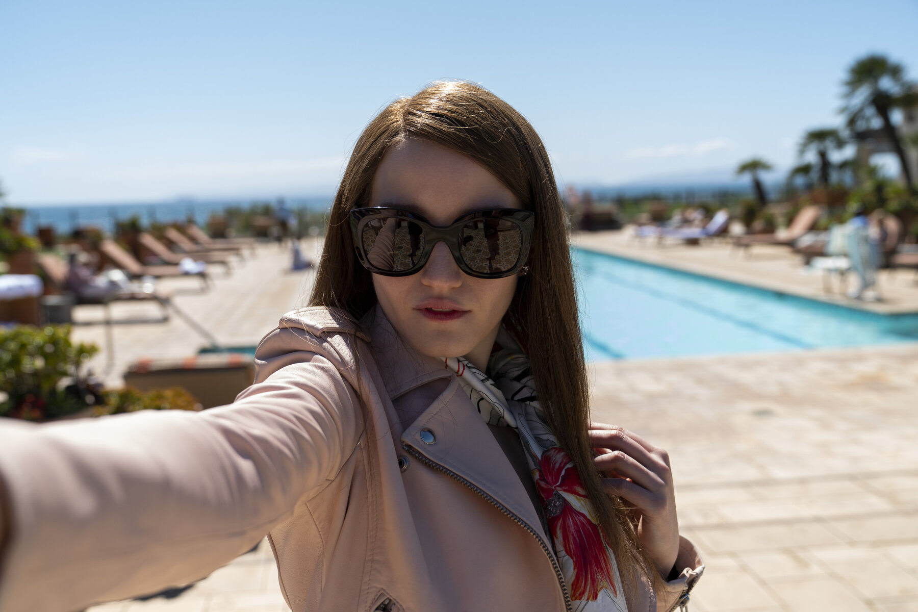 Young woman wearing dark glasses in front of a pool