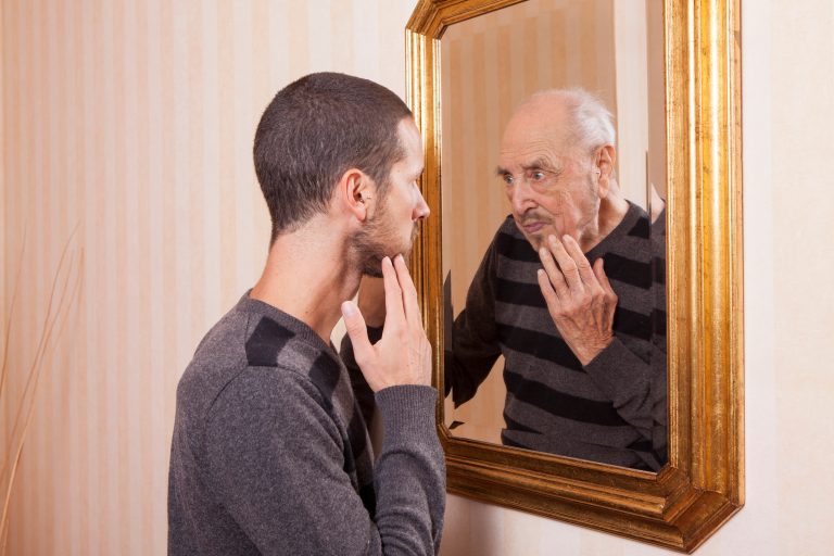 young man looking at aging self