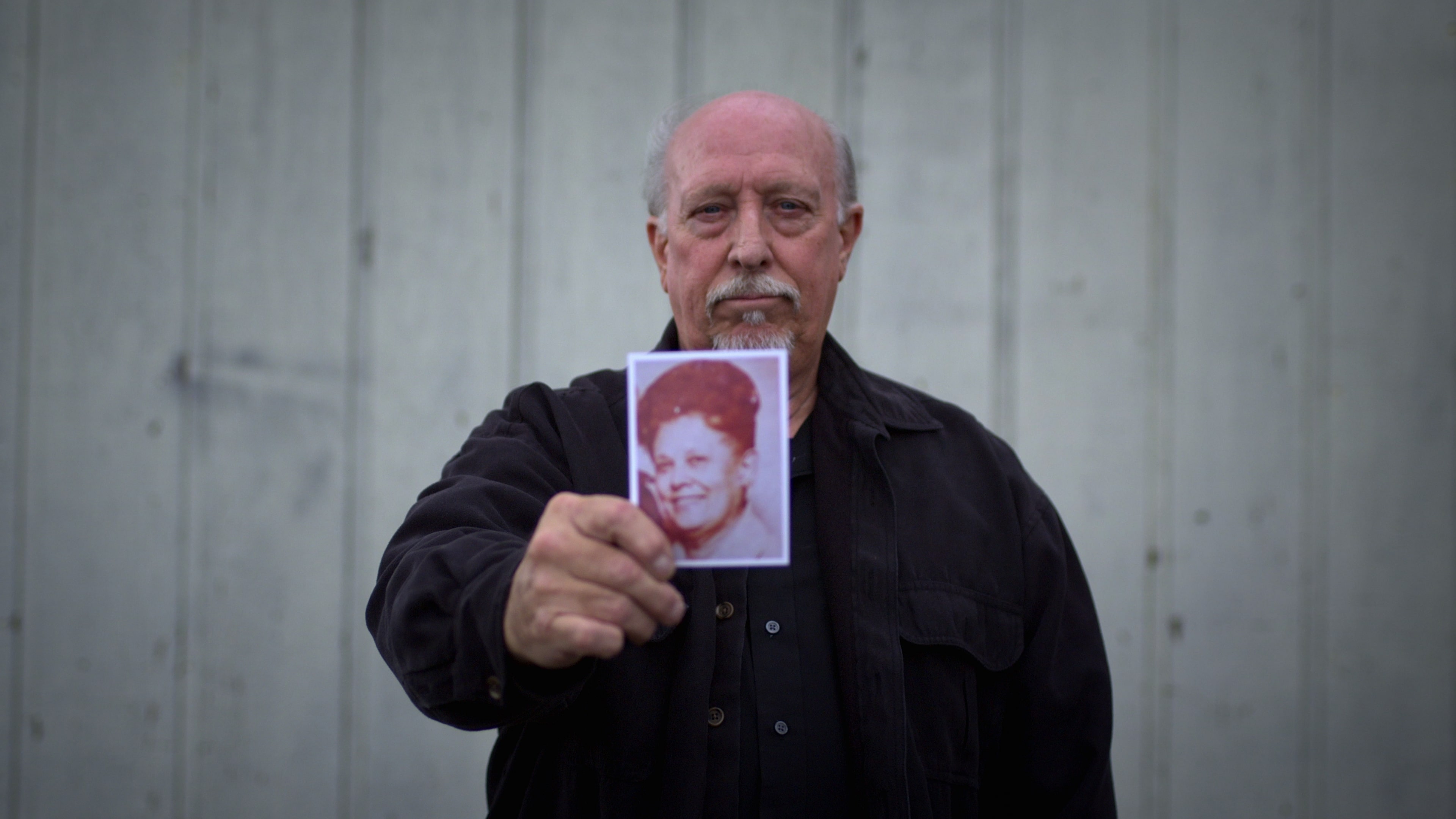 an old man holds a photograph