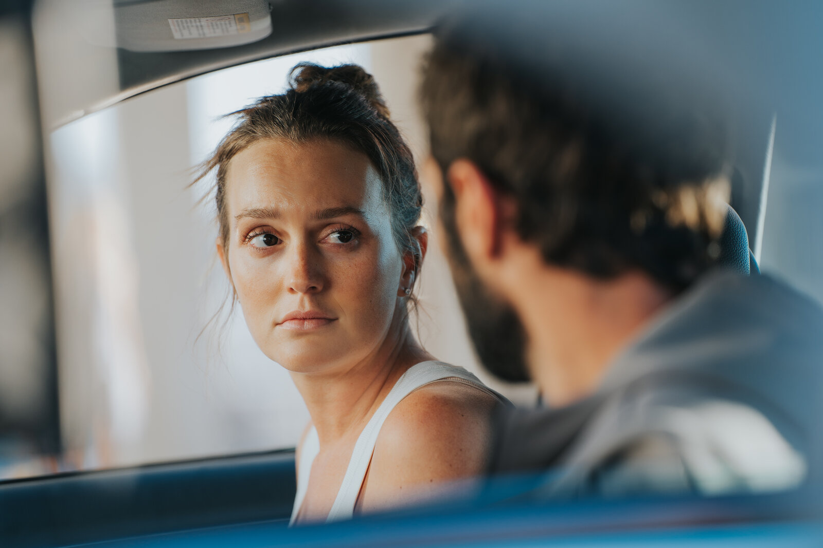 a woman in a car looking at a man