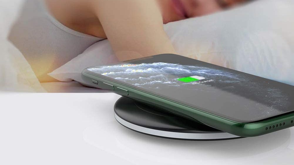 A woman asleep next to the charging pad with an iPhone 13 charging port showing