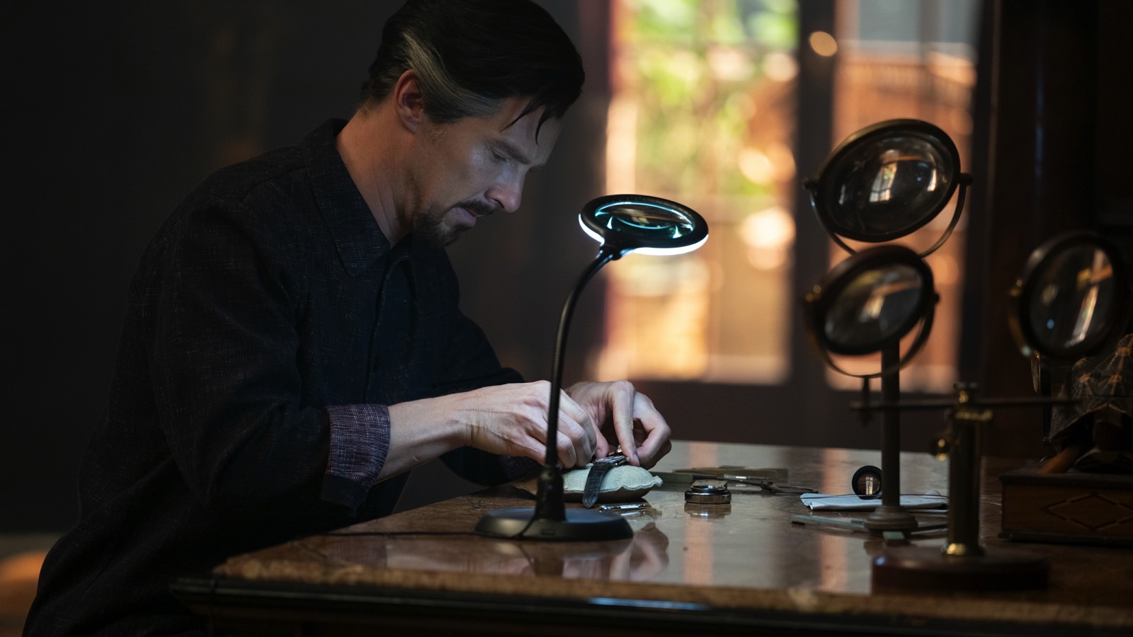 Doctor Strange (Benedict Cumberbatch) repairing his watch in a new still from Multiverse of Madness