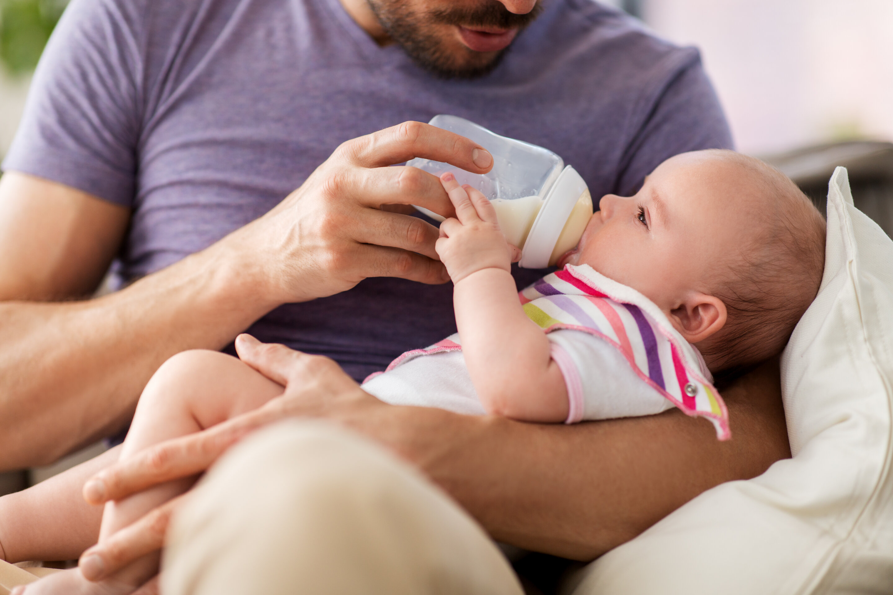 father holding and feeding a baby