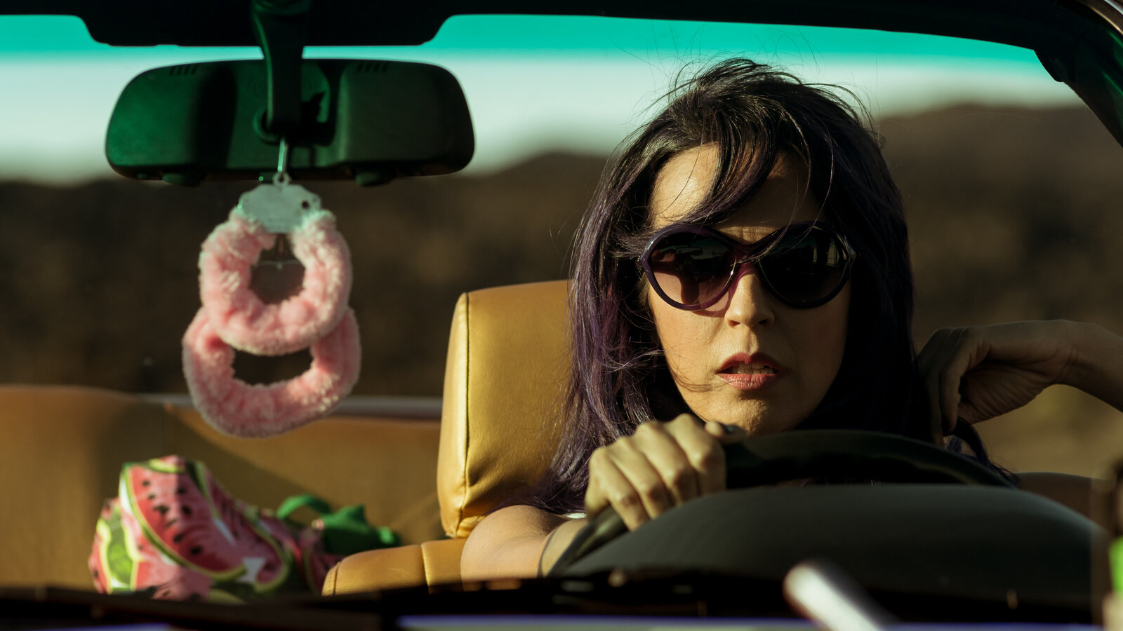 closeup of woman driving car wearing sunglasses