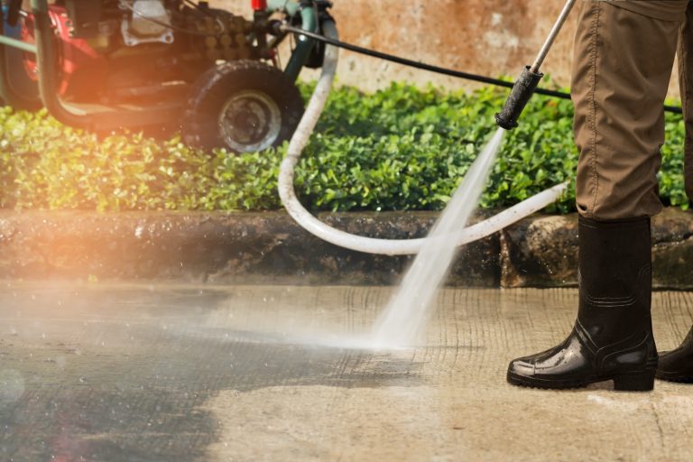 A person cleaning a driveway with a pressure washer.