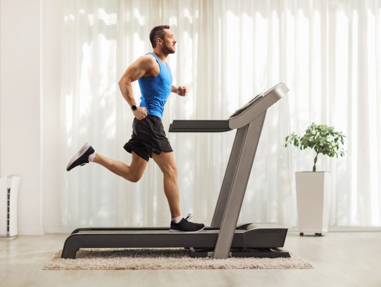 A young man running on a treadmill at home.