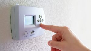 hand touching digital thermostat