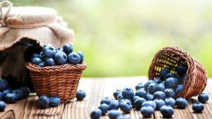 Blueberries in wicker basket on old table with back light.