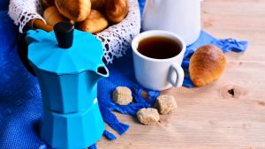 Coffee maker blue color on the background of croissants and utensils for coffee.