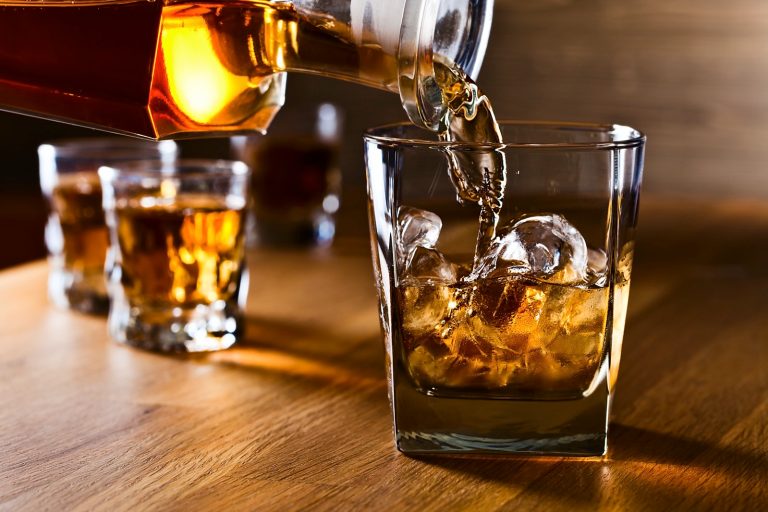 Whiskey and natural ice in a glass on old wooden table.