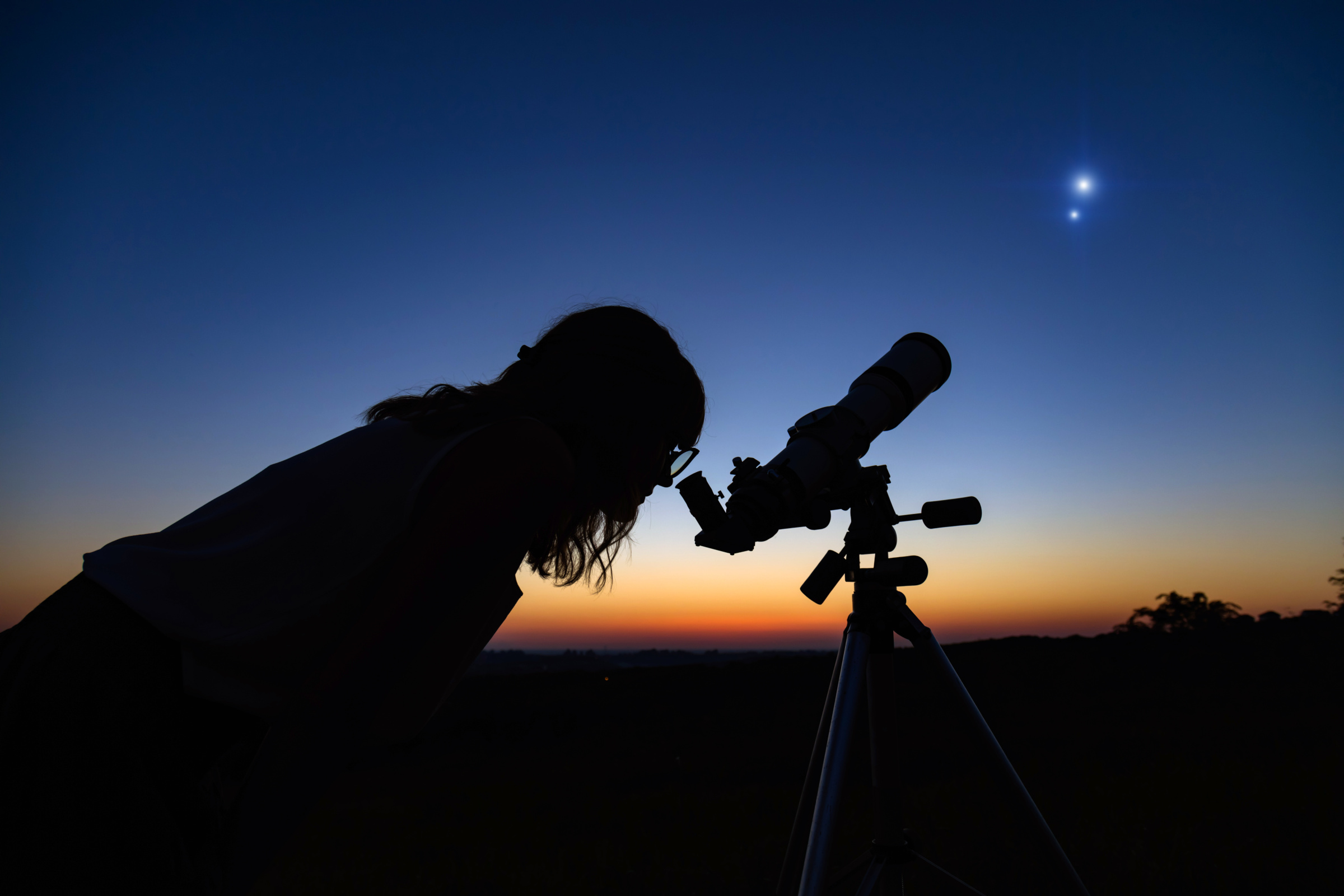 woman looking at planetary parade through telescope