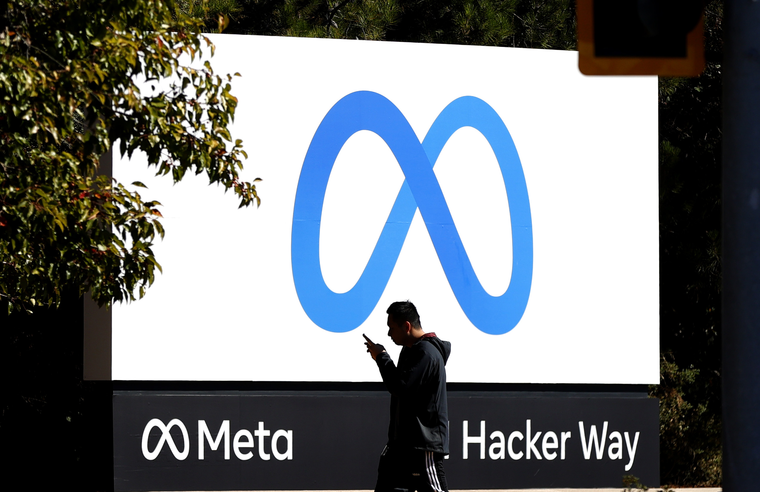 A pedestrian walks in front of a new logo and the name 'Meta' on the sign in front of Facebook headquarters on October 28, 2021 in Menlo Park, California.