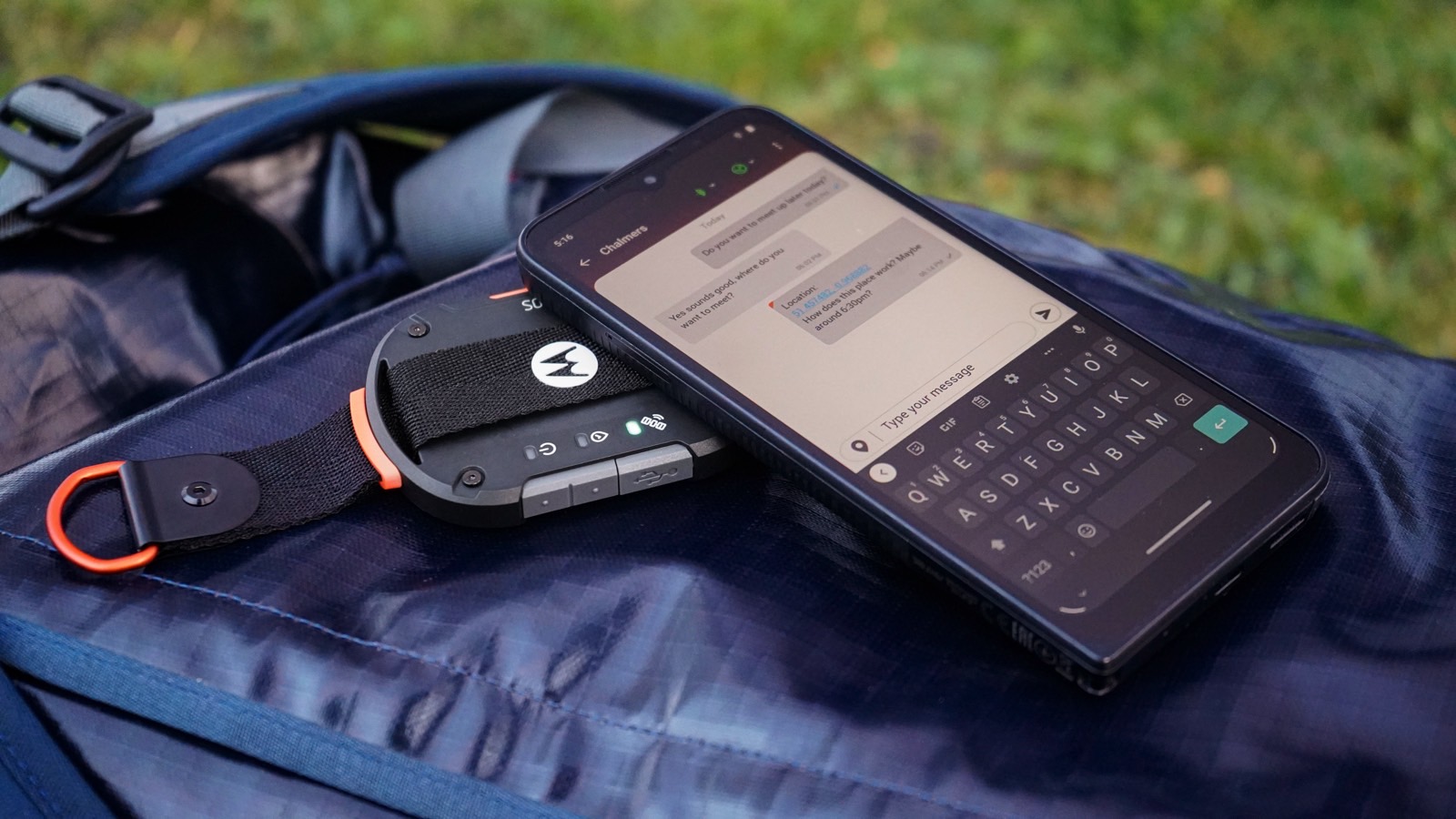 Two-way texting via satellite on a phone connected to the Motorola Defy Satellite Link device next to it.