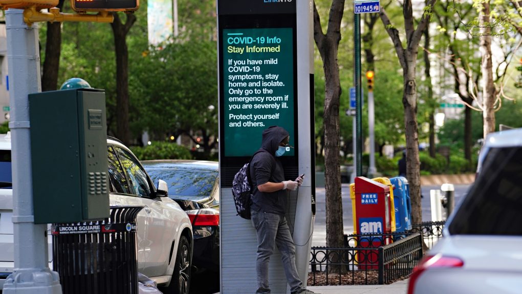 A man wearing a protective mask leans against a LinkNYC box displaying COVID-19 information during the coronavirus pandemic on May 07, 2020 in New York City.