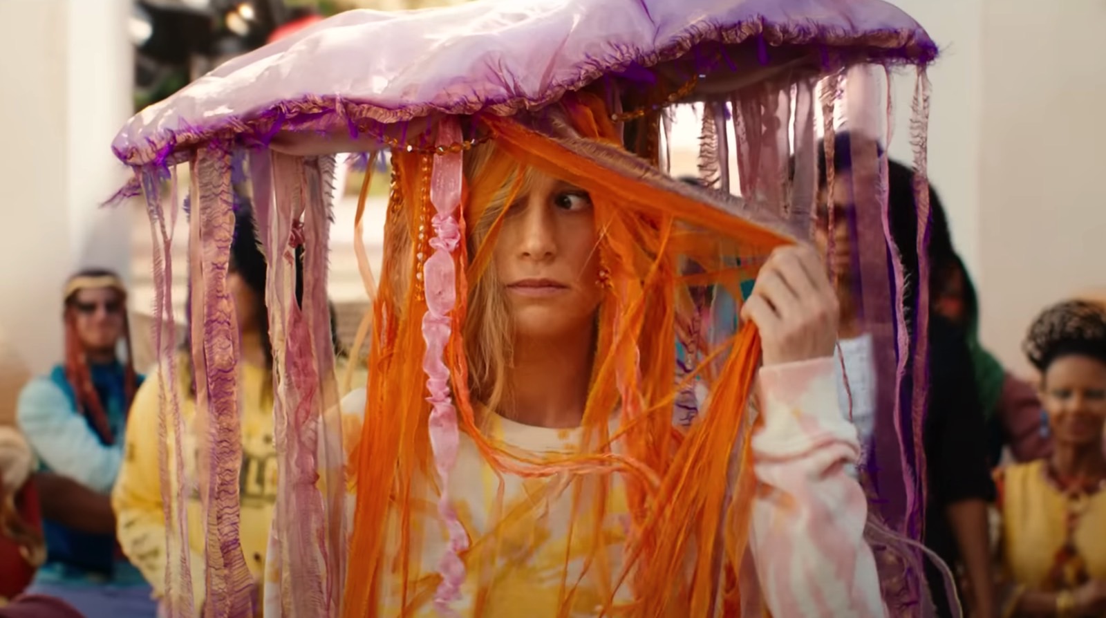 Carol Danvers (Brie Larson) in disguise, as people dance around her.