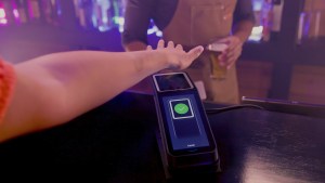 Someone using Amazon One palm recognition technology to buy a beer