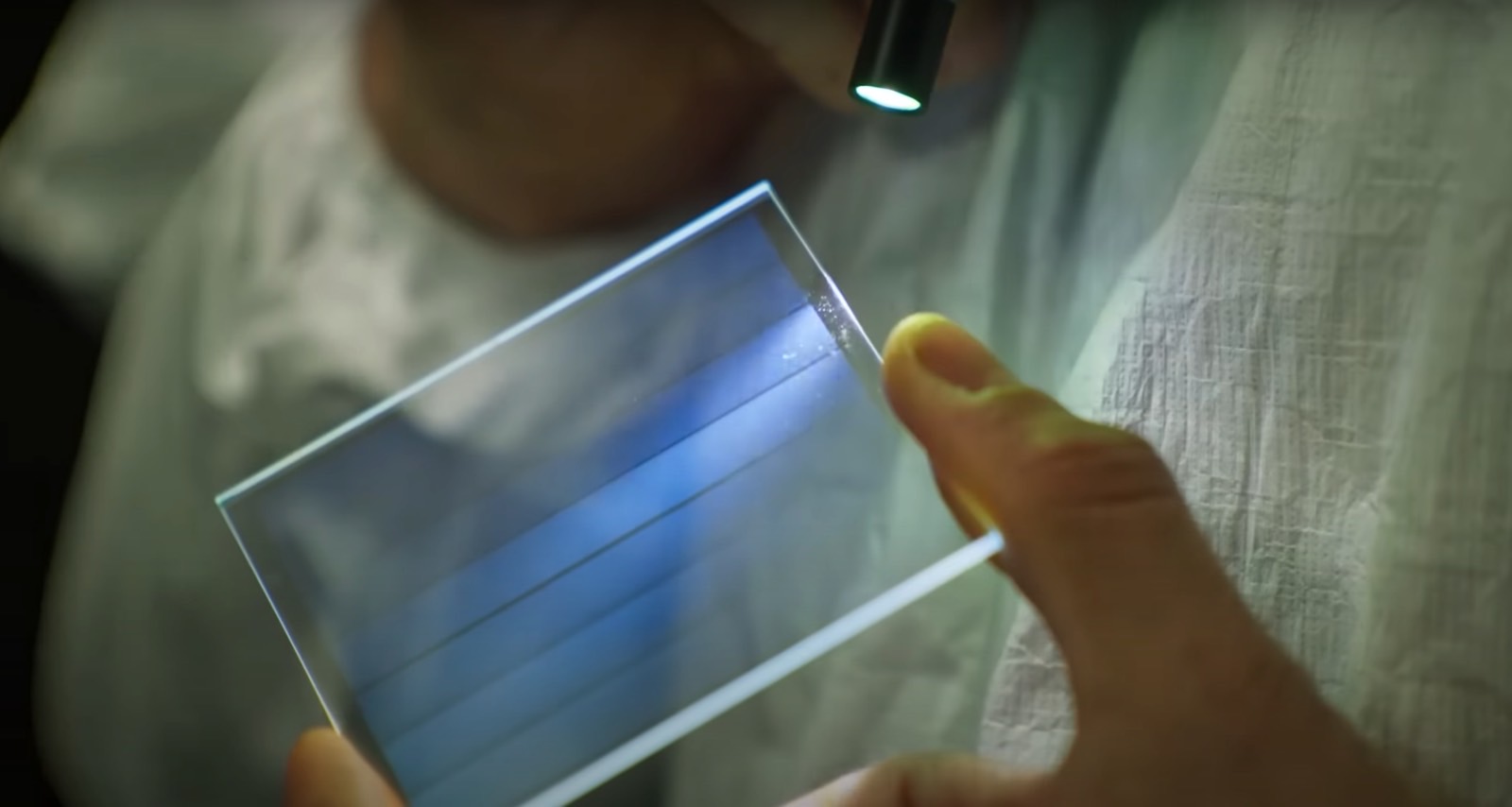 A person inspecting a sheet of glass containing data.