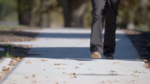 person walks on coffee-reinforced concrete footpath