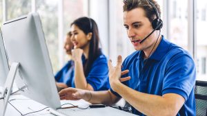 emotion-canceling AI Group of happy call center smiling business operator customer support team phone services agen working and talking with headset on desktop computer at call center
