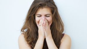 why we blush Embarrassed girl laughing and covering mouth with hands
